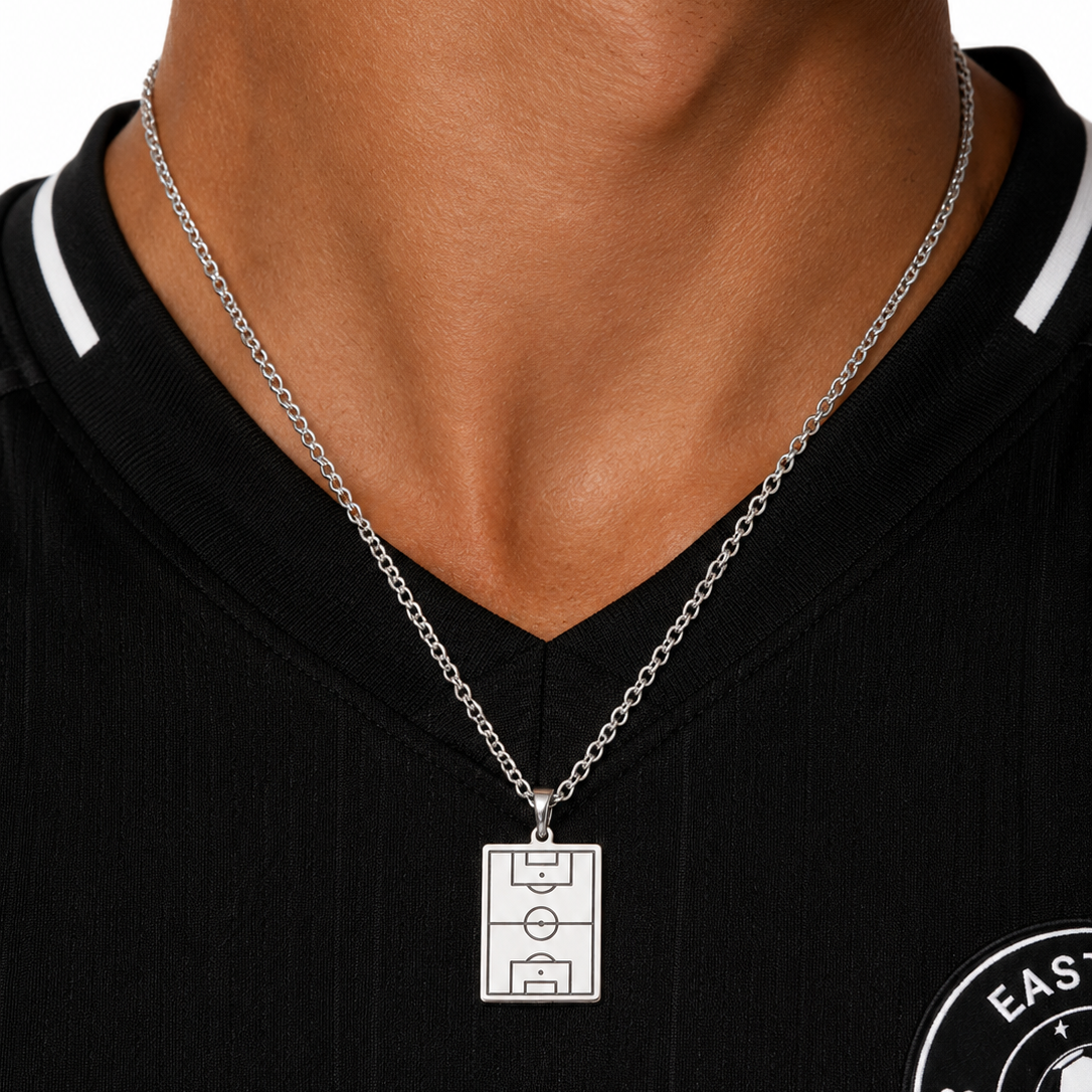 Person wearing a necklace with a sports field pendant on a black shirt.