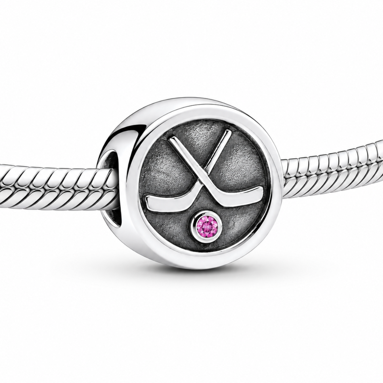 Silver charm with hockey stick design and pink gemstone on a white background
