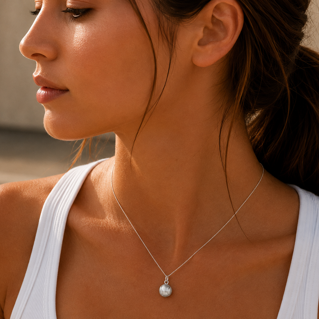 Close-up of a woman wearing a silver necklace with a pendant against a neutral background